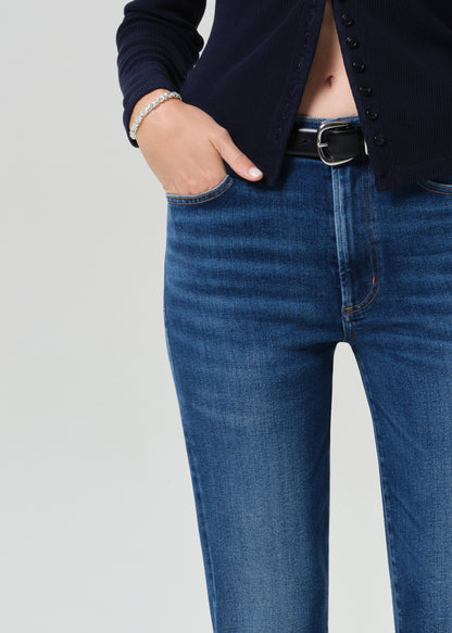 Person wearing a navy cardigan and blue jeans on a grey background