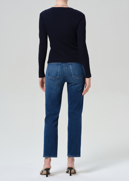 Person wearing a navy cardigan and blue jeans on a grey background