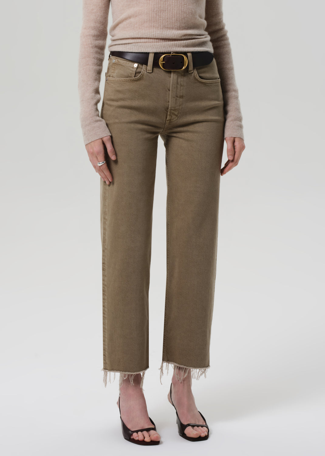Person wearing beige high-waisted jeans with a belt on a white background
