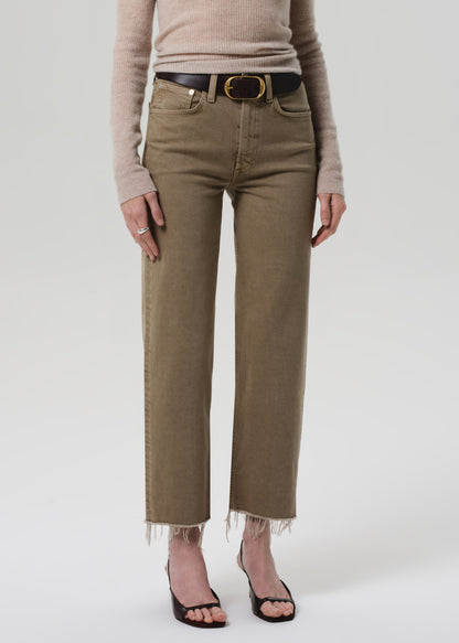 Person wearing beige high-waisted jeans with a belt on a white background