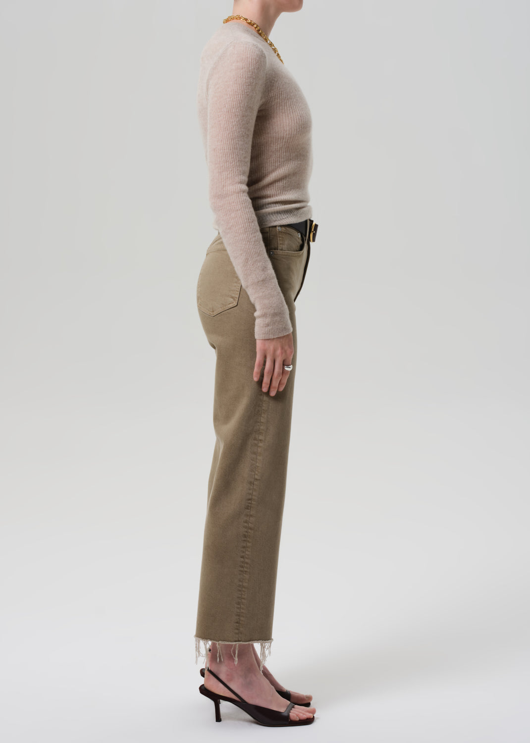 Person wearing a beige sweater and khaki pants on a white background