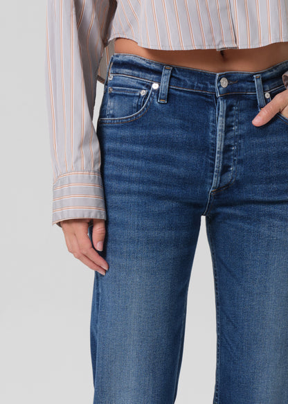 Person wearing a light gray stripe shirt and blue jeans on a grey background