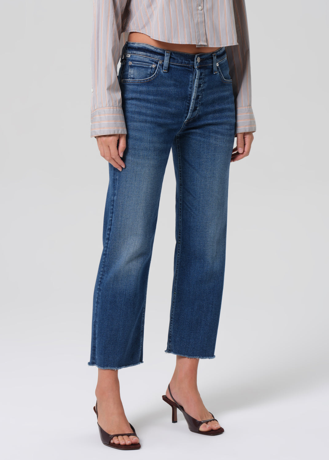 Person wearing a light gray stripe shirt and blue jeans on a grey background