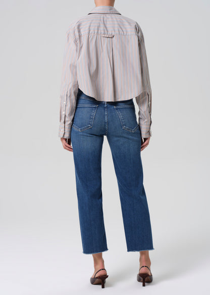 Person wearing a light gray stripe shirt and blue jeans on a grey background