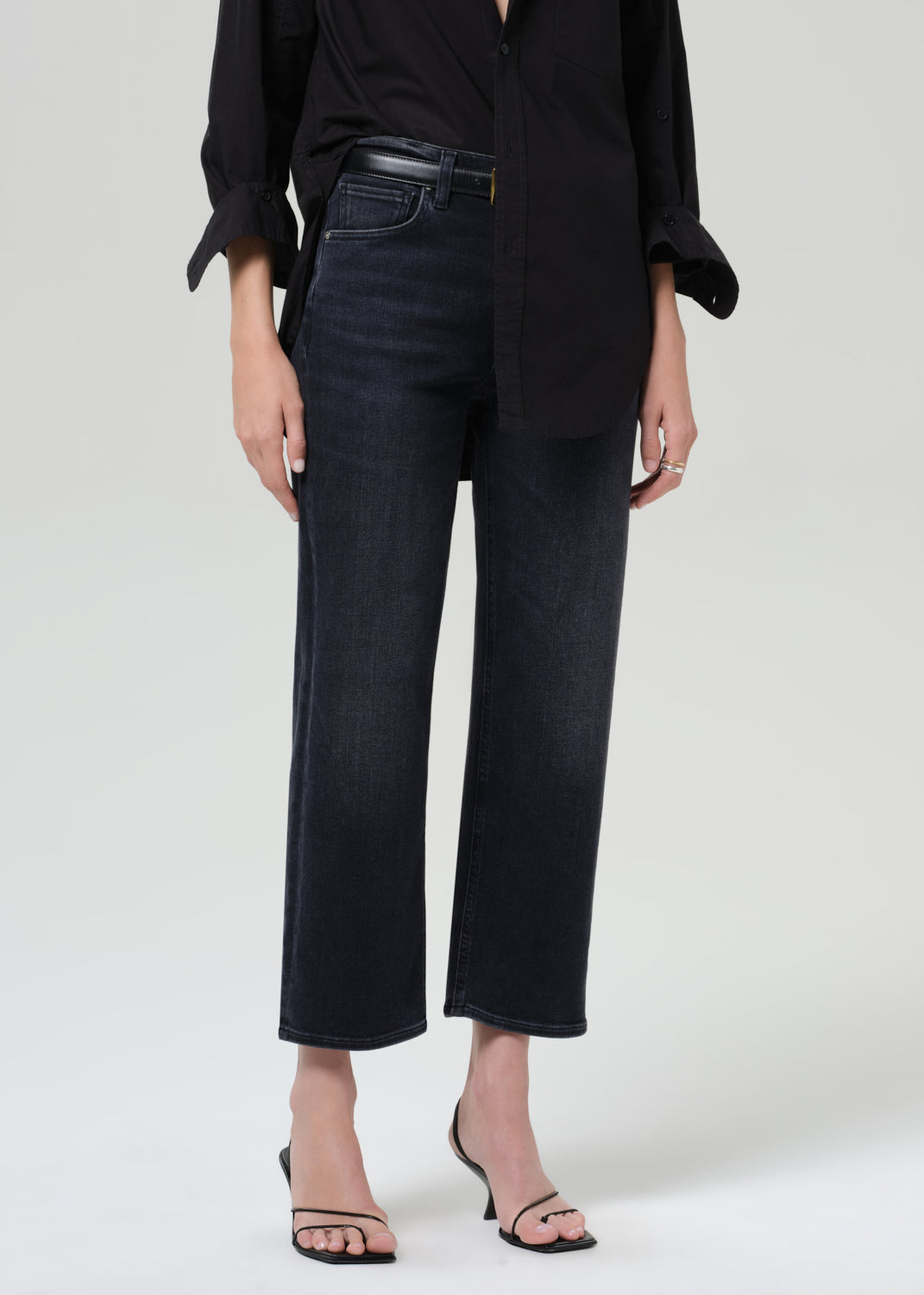 Person wearing a black shirt and black jeans on a grey background