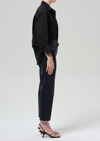 Person wearing a black shirt and black jeans on a grey background