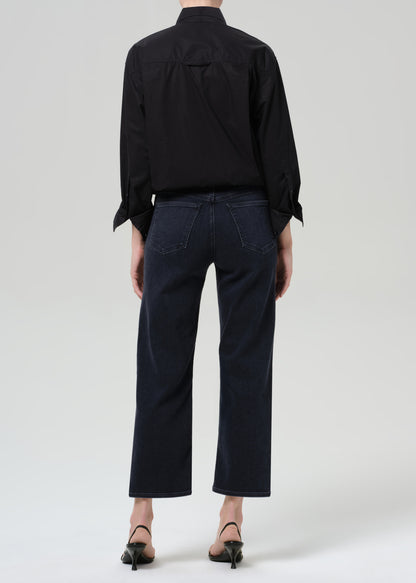 Person wearing a black shirt and black jeans on a grey background