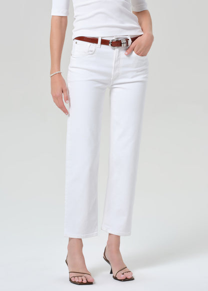 Person wearing a white shirt and white pants with a brown belt on a plain background