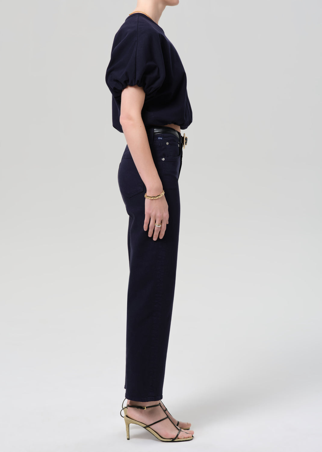 Person wearing a navy outfit with a top and pants on a grey background