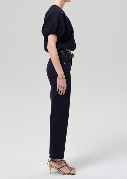 Person wearing a navy outfit with a top and pants on a grey background