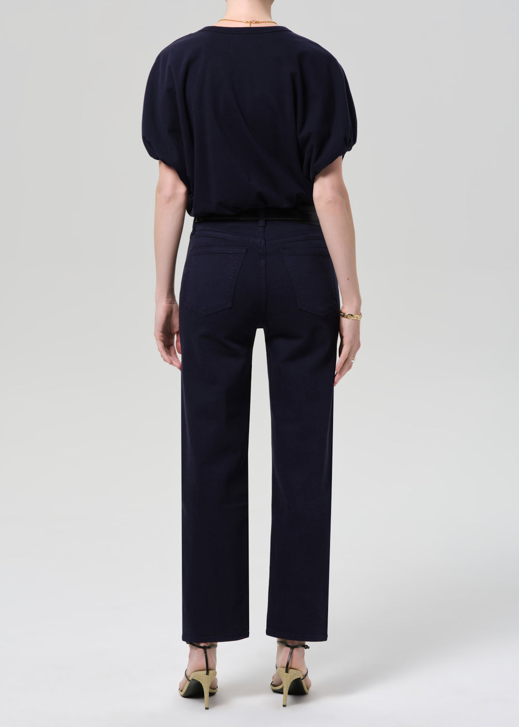 Person wearing a navy outfit with a top and pants on a grey background