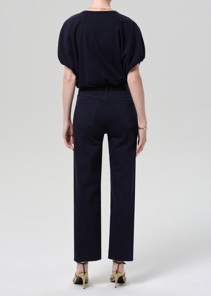 Person wearing a navy outfit with a top and pants on a grey background