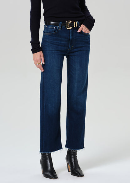 Person wearing blue jeans and black boots on a grey background