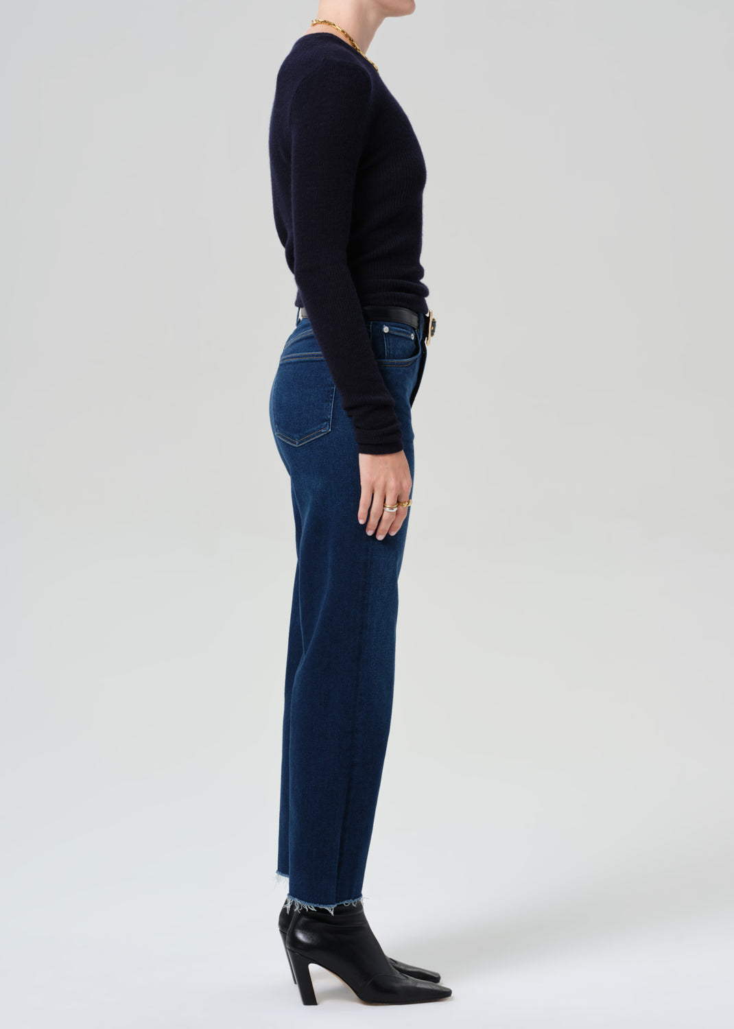 Person wearing a dark blue sweater and jeans on a white background