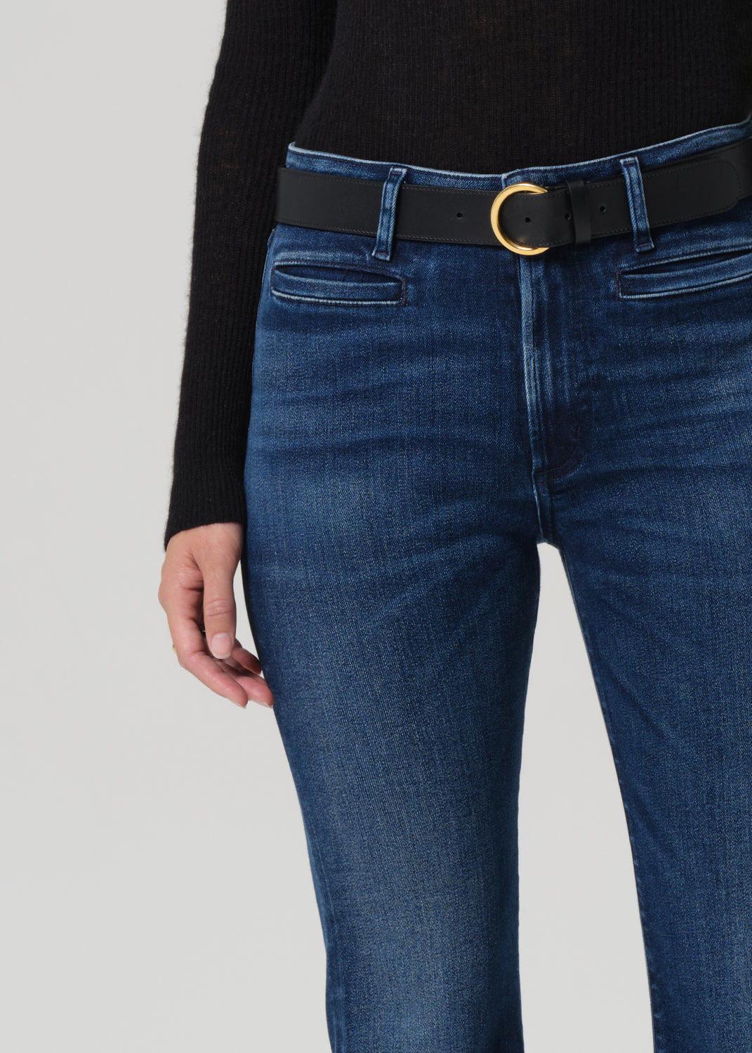 Blue jeans with a black belt and gold buckle on a gray background