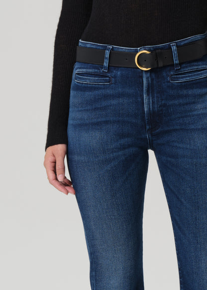 Blue jeans with a black belt and gold buckle on a gray background