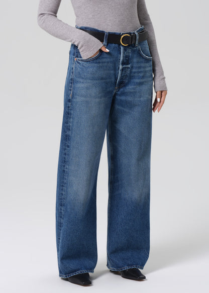 Person wearing blue jeans and a gray sweater on a grey background