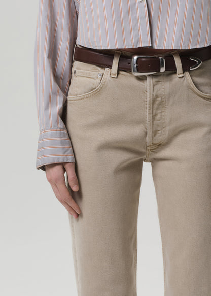 Person wearing beige pants with a brown belt and striped shirt on a light gray background