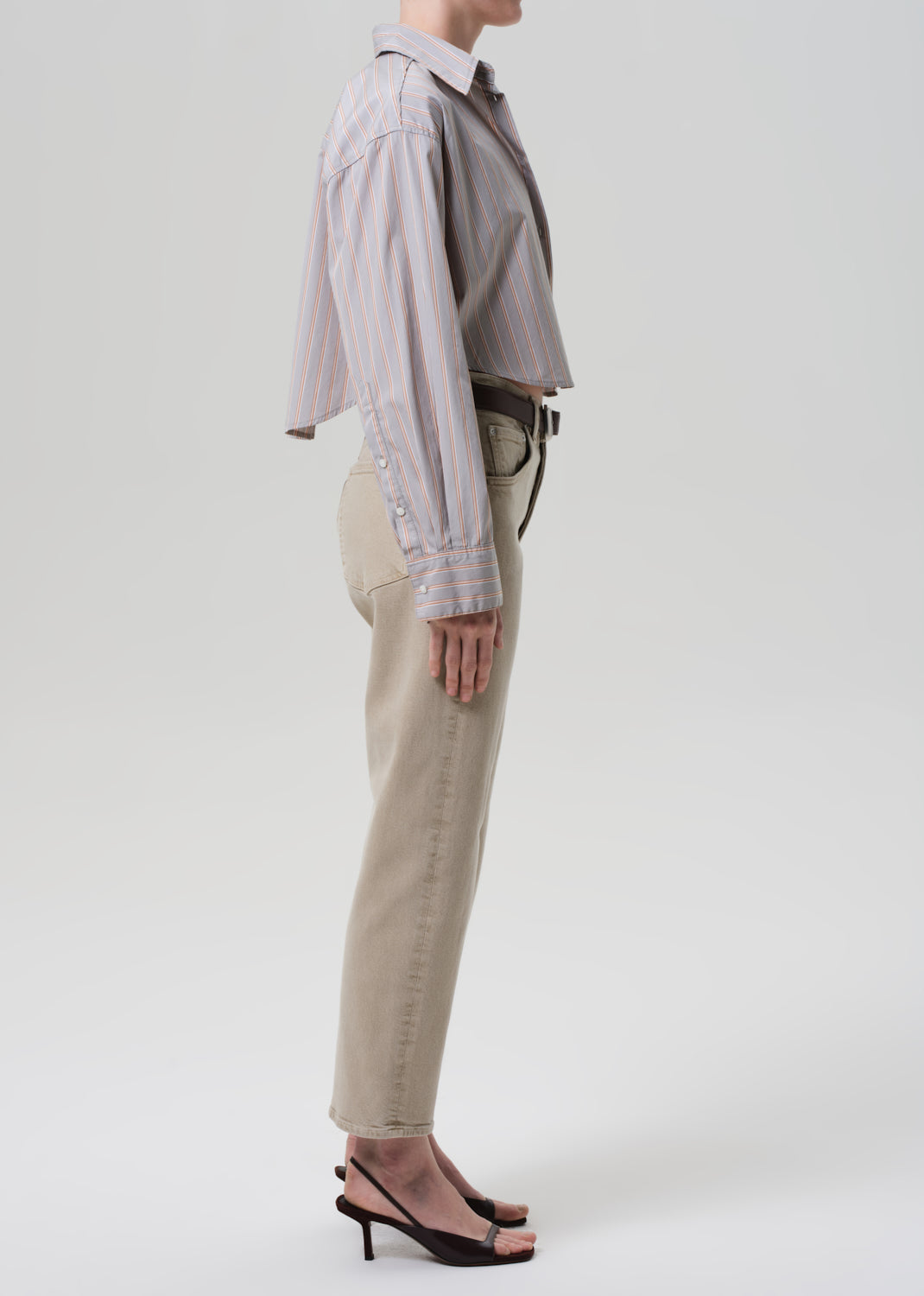 Person wearing a light gray shirt and beige pants on a white background