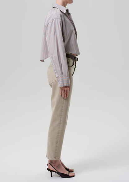 Person wearing a light gray shirt and beige pants on a white background