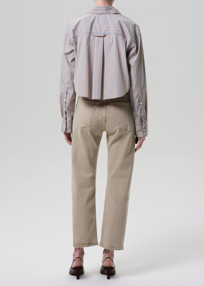 Person wearing a light gray shirt and beige pants on a white background