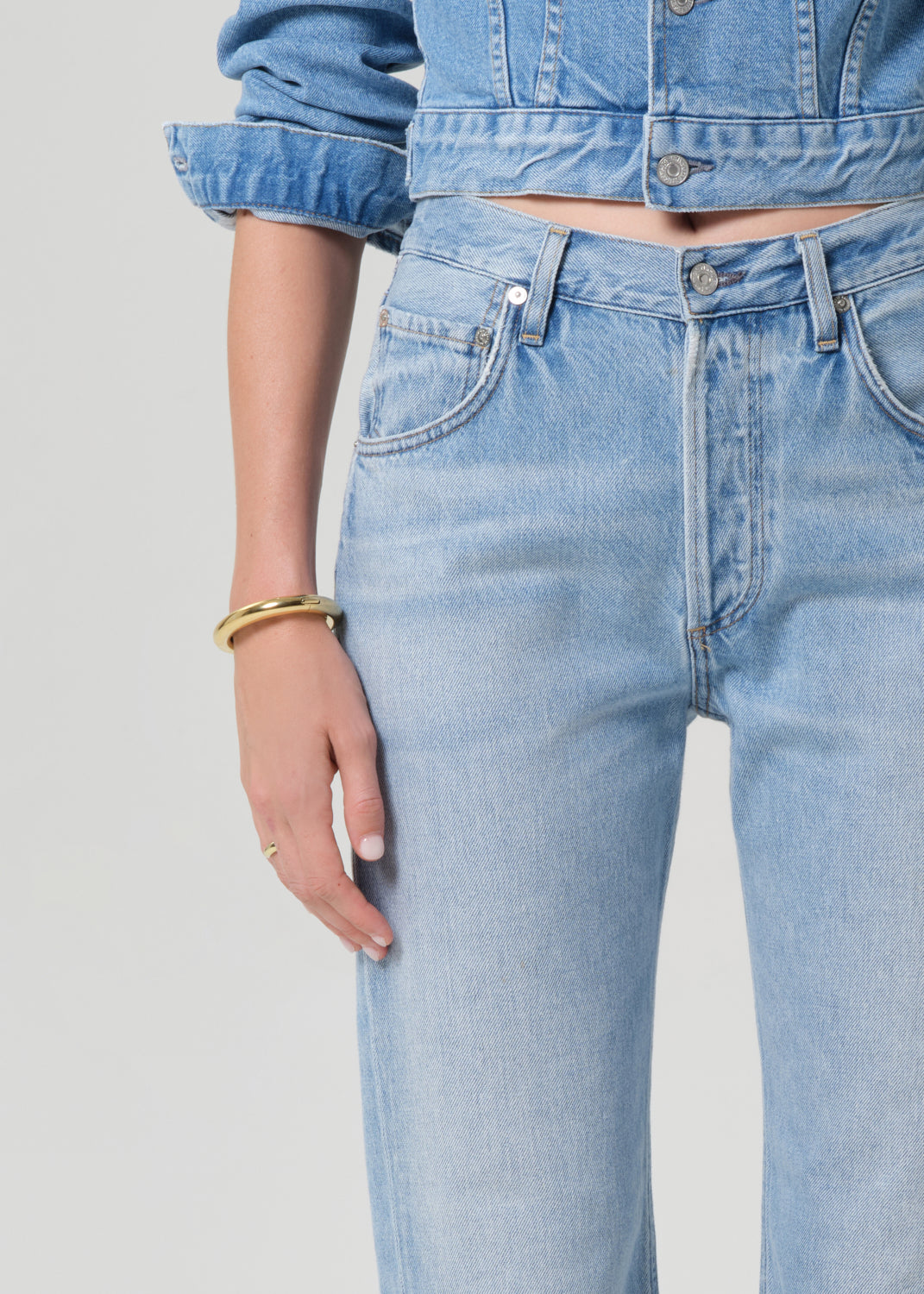 Light blue jeans worn by a person on a gray background