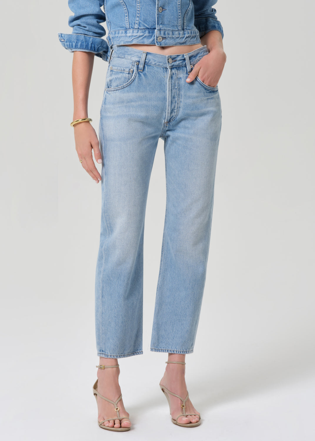 Person wearing a denim jacket and jeans on a grey background