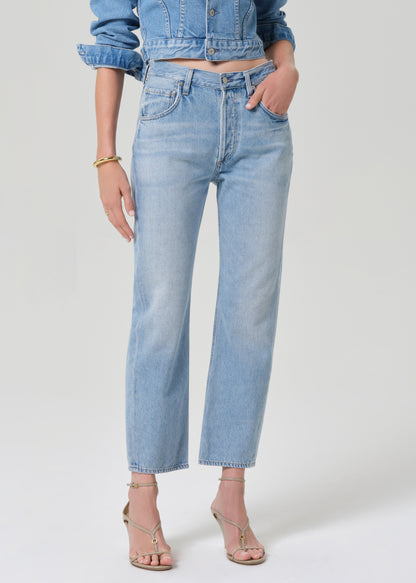 Person wearing a denim jacket and jeans on a grey background