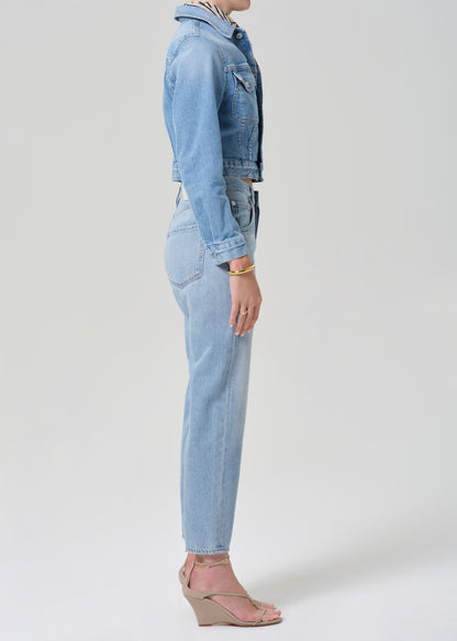 Person wearing a denim jacket and jeans on a grey background