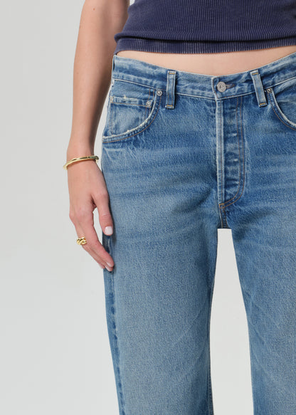 Person wearing a navy blue tee and light blue jeans on a grey background
