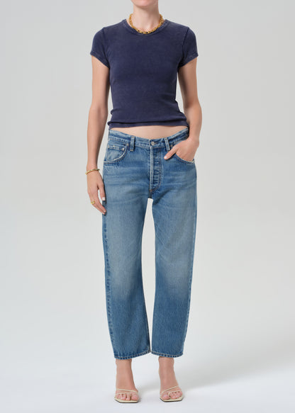 Person wearing a navy blue tee and light blue jeans on a grey background