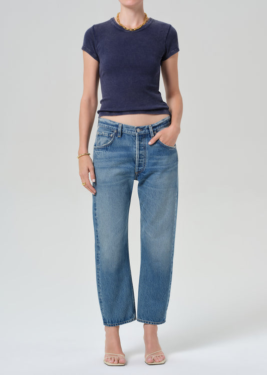 Person wearing a navy blue tee and light blue jeans on a grey background