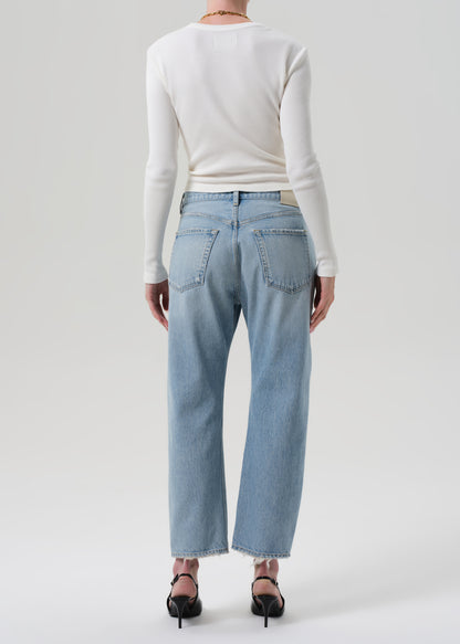 Person wearing light blue jeans and a white long-sleeve shirt on a plain background