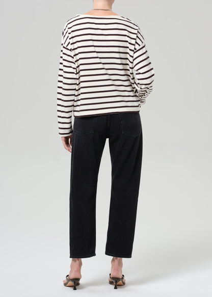 Person wearing a brown and white striped shirt and black jeans on a plain background