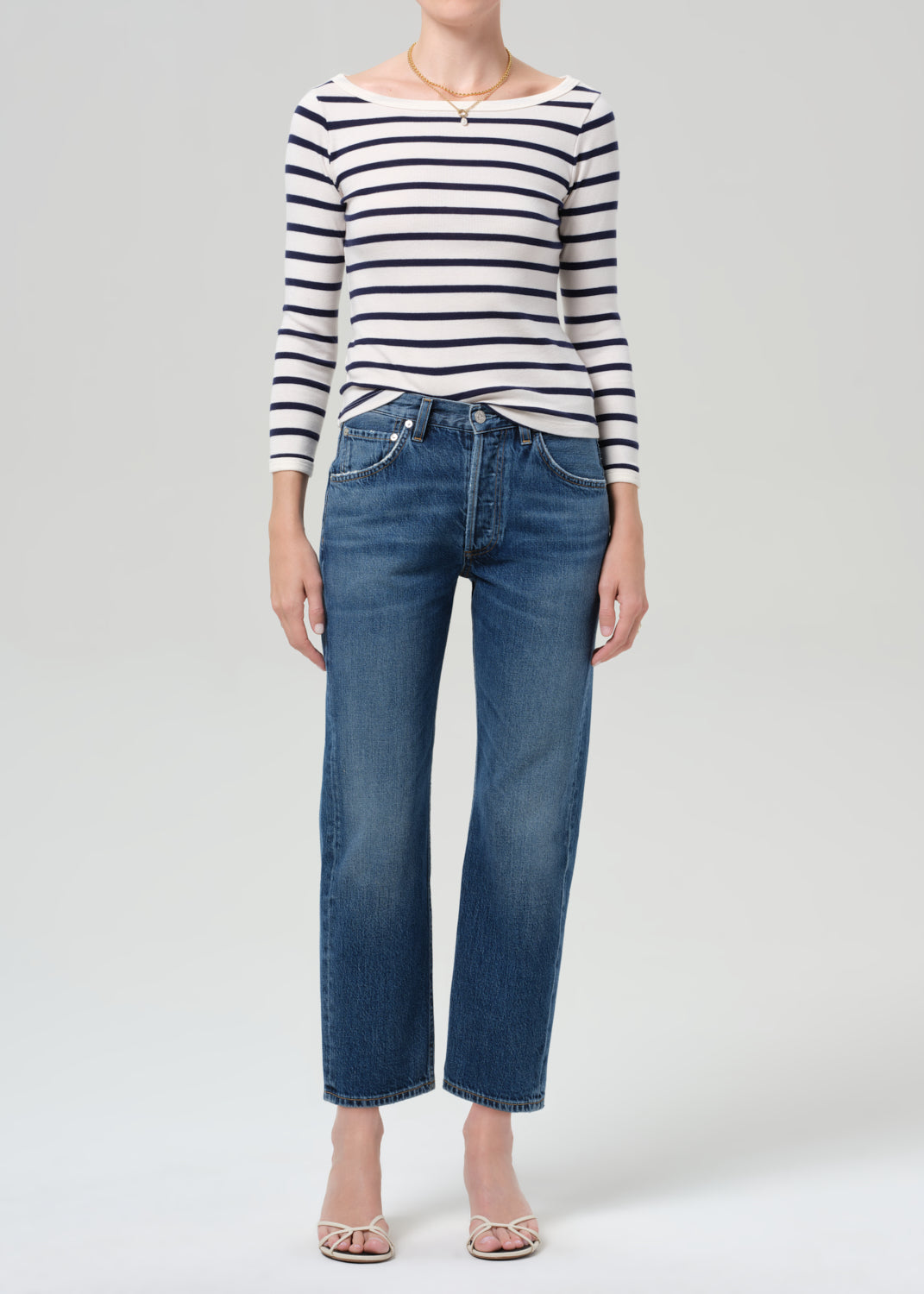Person wearing a striped shirt and blue jeans on a grey background