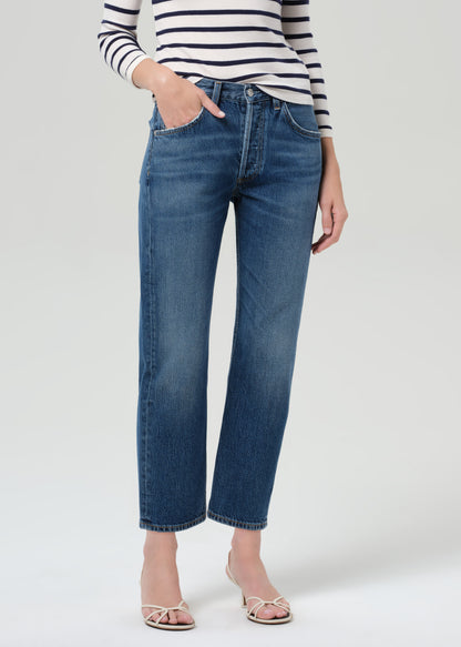 Person wearing a striped shirt and blue jeans on a grey background