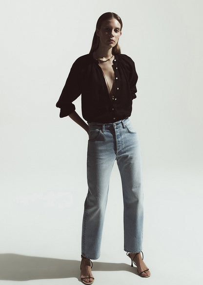 Woman wearing a brown shirt and light blue jeans on a grey background