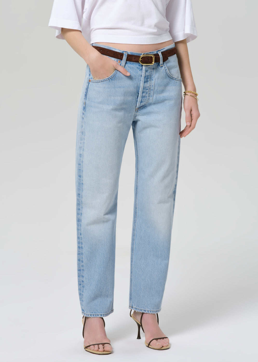 Person wearing light blue jeans and a white shirt on a plain background