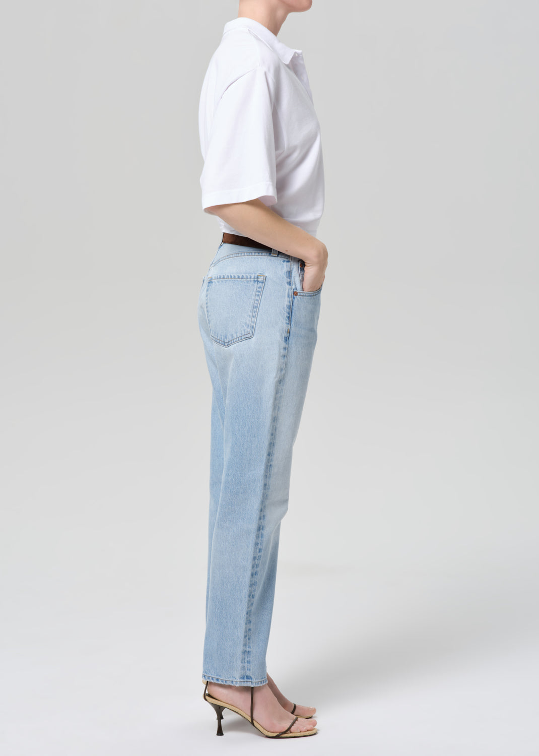 Person wearing light blue jeans and a white shirt on a plain background