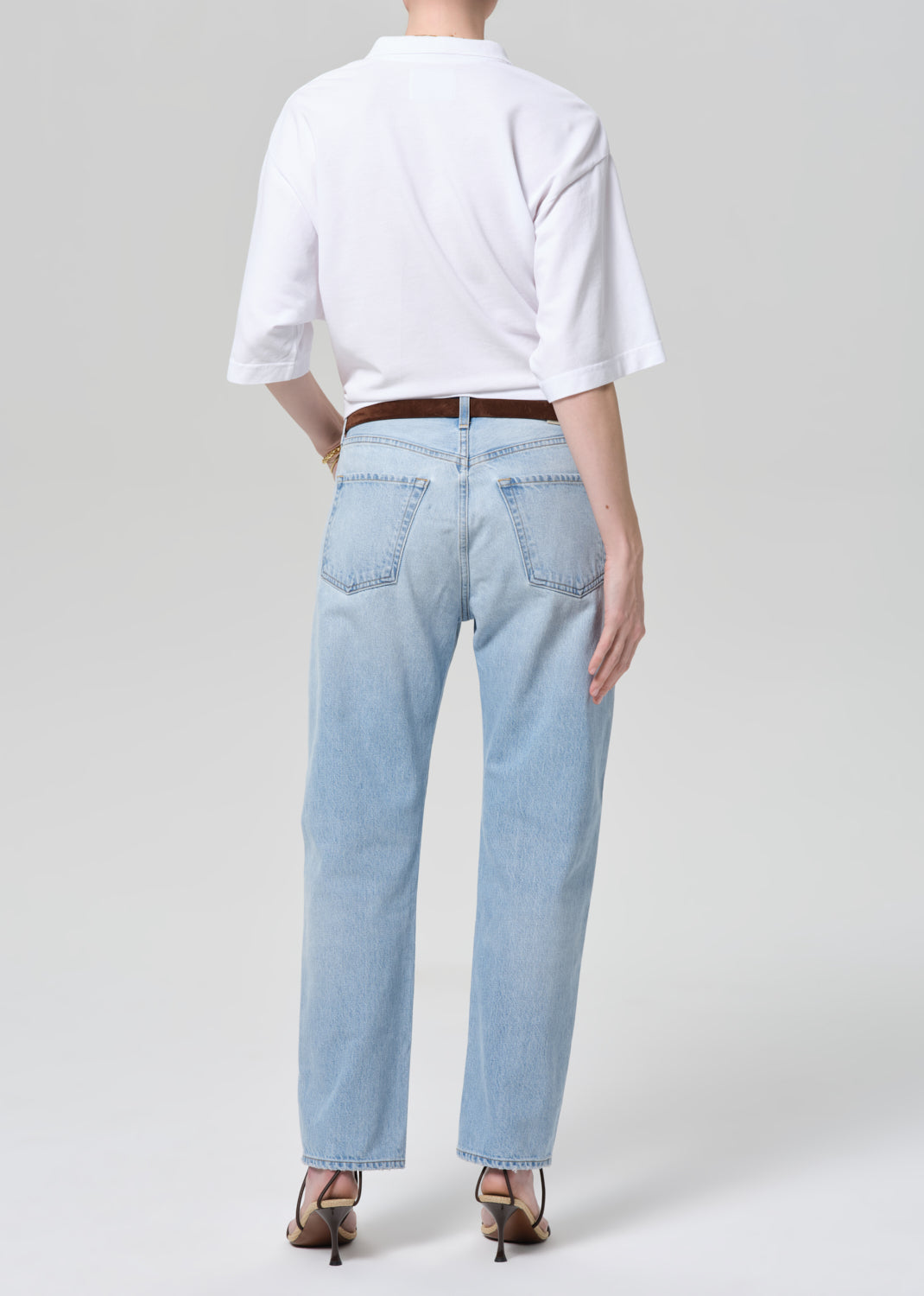 Person wearing light blue jeans and a white shirt on a plain background