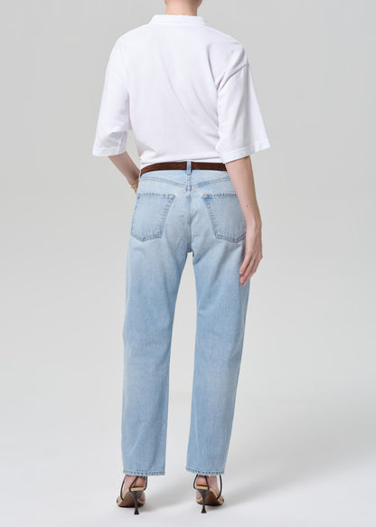 Person wearing light blue jeans and a white shirt on a plain background