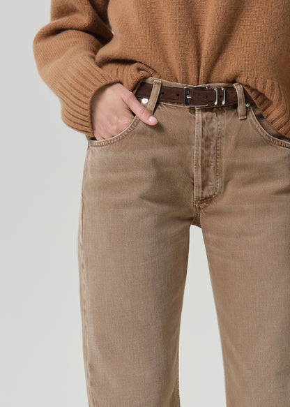 Person wearing tan straight leg pants on a grey background