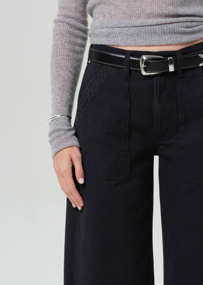 Person wearing a gray sweater and black wide-leg pants on a grey background