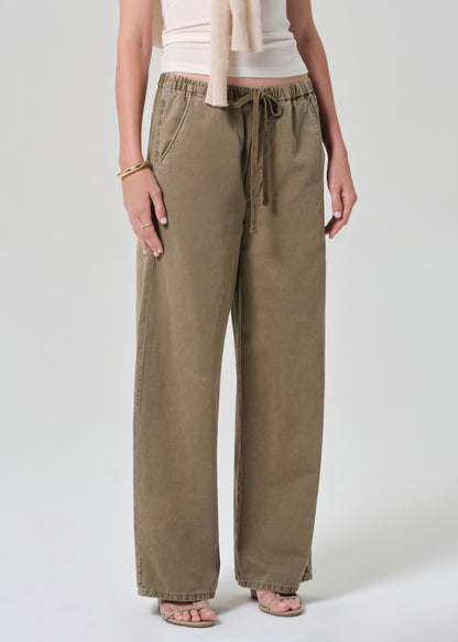 Person wearing a white t-shirt and olive brown wide-leg pants on a grey background