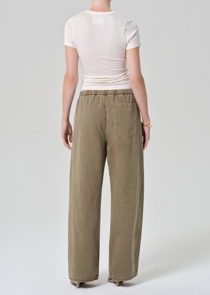 Person wearing a white t-shirt and olive brown wide-leg pants on a grey background