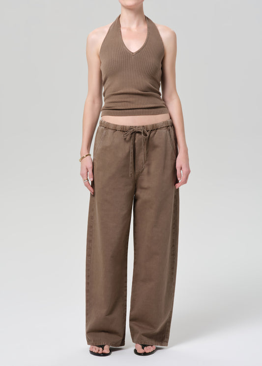 Person wearing a brown ribbed tank top and wide-leg pants on a plain background