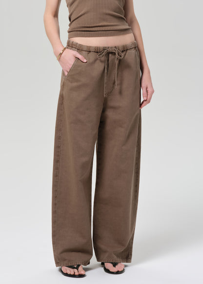 Person wearing a brown ribbed tank top and wide-leg pants on a plain background