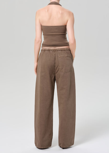 Person wearing a brown ribbed tank top and wide-leg pants on a plain background