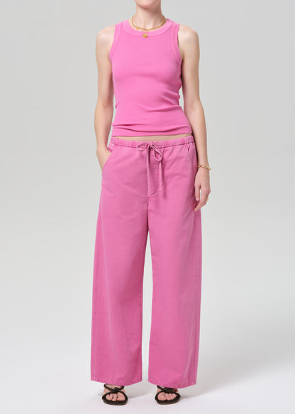 Person wearing a pink sleeveless top and wide-leg pants on a plain background