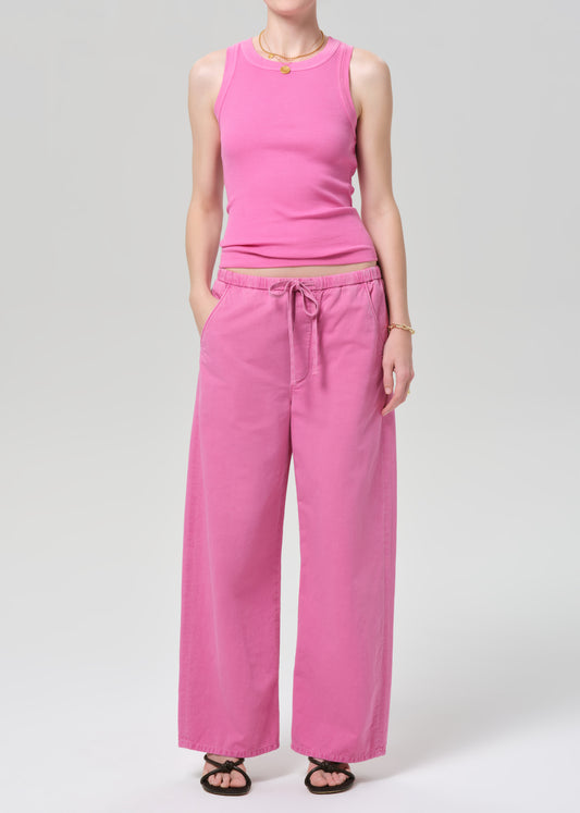 Person wearing a pink sleeveless top and wide-leg pants on a plain background